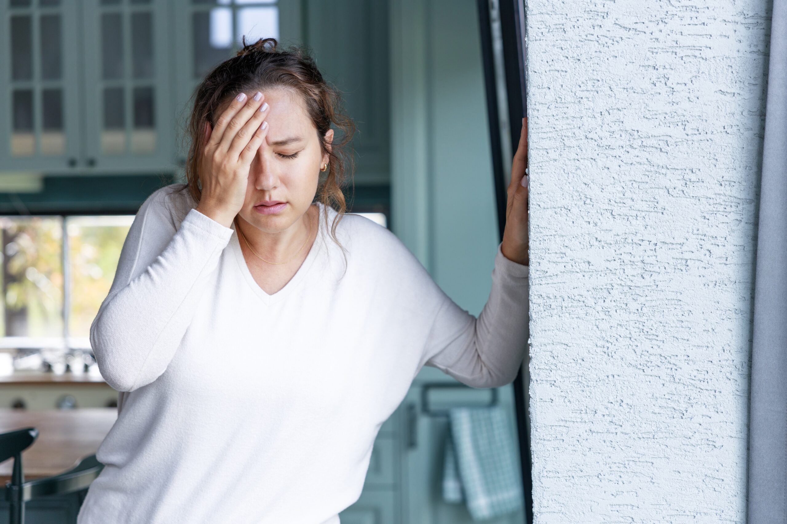 young woman appears in pain with hand on forehead