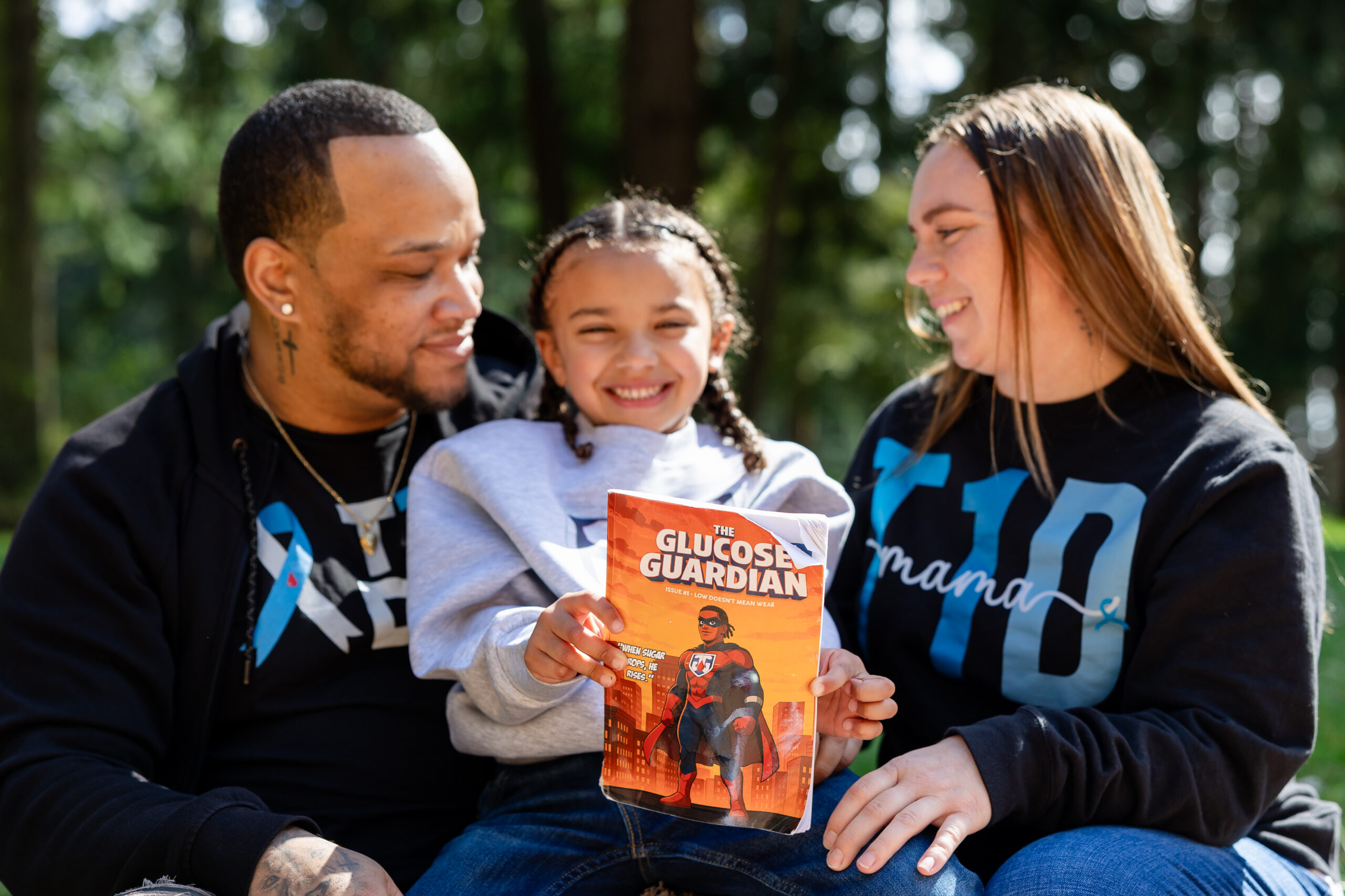 Kid holds a book while sitting between parents