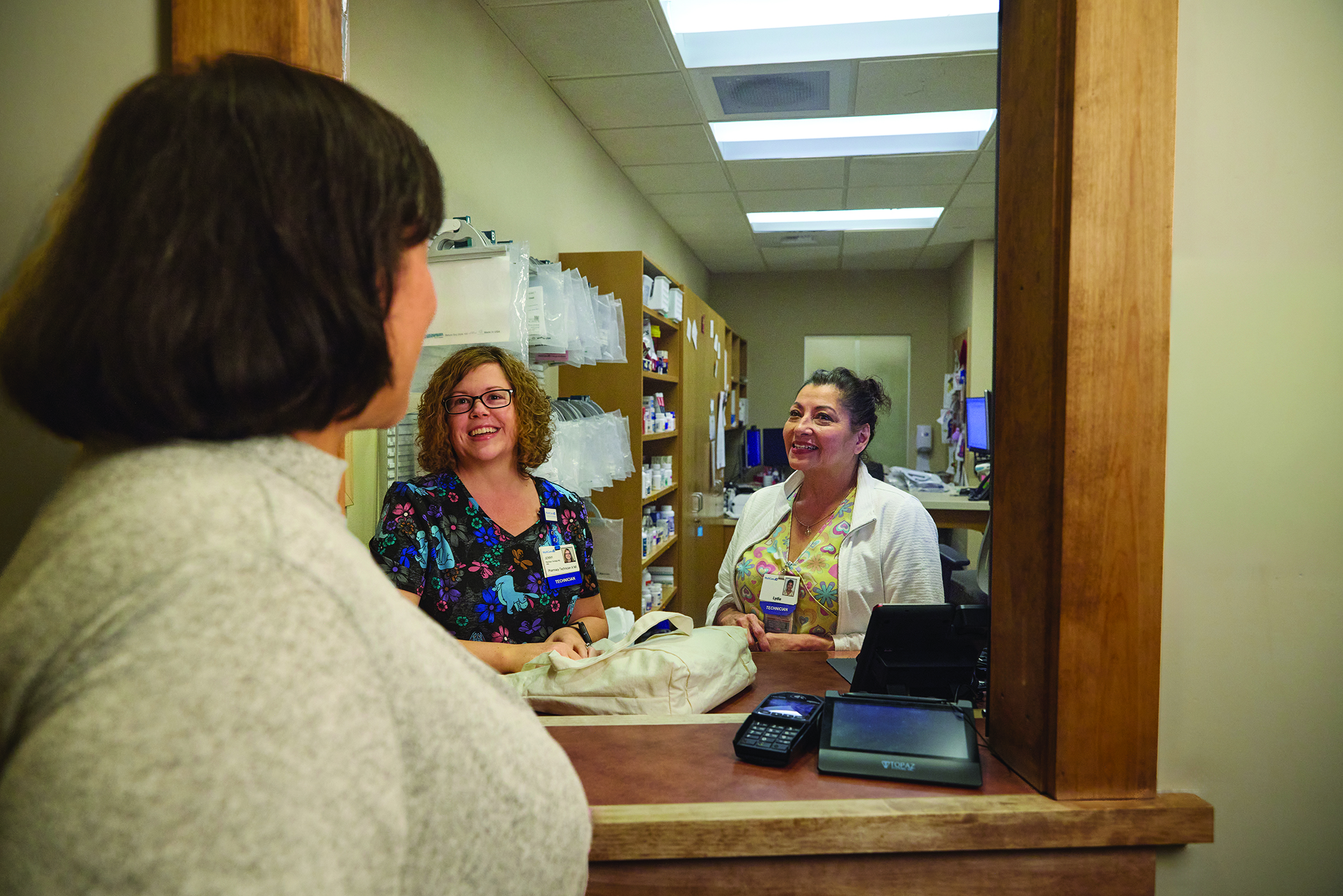 Three women talking at pharmacy window