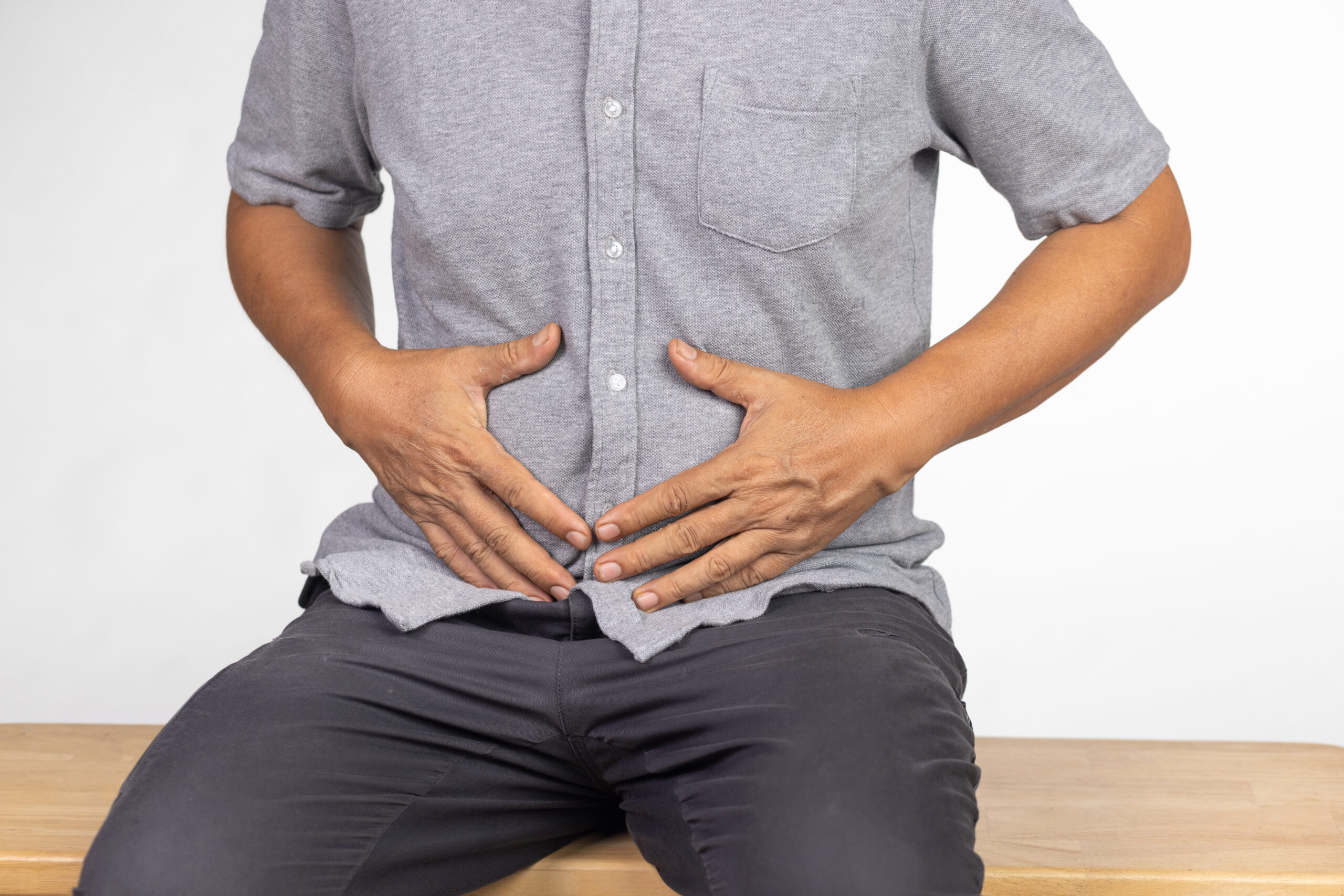 man sitting and holding lower abdomen