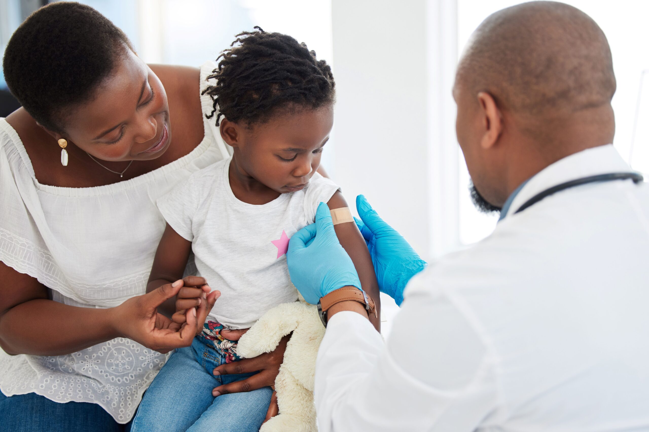 A child sits between their mother and doctor after receiving a vaccine